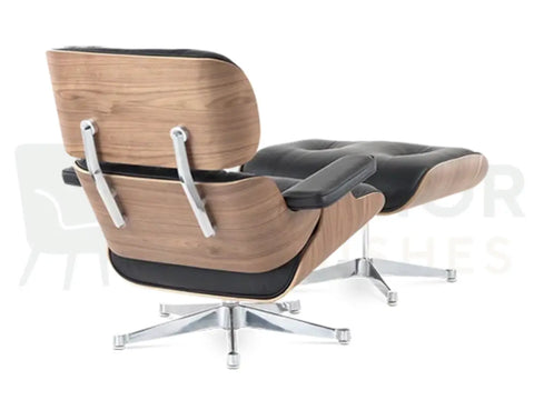 A mid-century modern lounge chair with a matching ottoman, featuring a light wood grain shell, black leather cushions, and a chrome five-star base, shown against a white background.